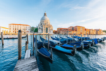 Naklejka premium Venetian gondolas moored at dawn, Basilica backdrop.