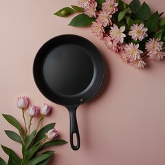 Creative concept with spring flowers and green leaves in frying pan on pastel pink background.