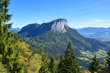 Fototapeta premium Majestic mountain with steep cliff face, nestled amidst green forests and clear skies