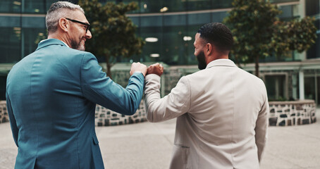 Business people, fist bump and team celebrate outdoor in city for success, win or deal bonus. Back of men, friends or corporate colleagues together for gesture, partnership or excited for opportunity