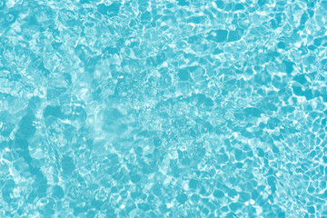 Blue water with ripples on the surface. Defocus blurred transparent blue colored clear calm water surface texture with splashes and bubbles. Water waves with shining pattern texture background.