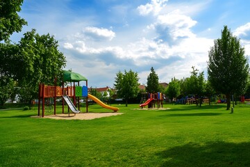 Playground on green lawn with slides and climbing structures under blue sky