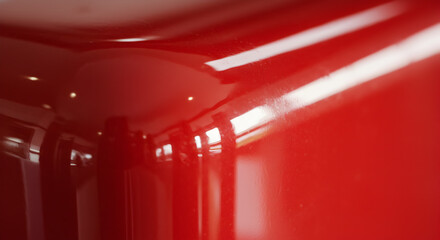 Abstract close-up of a glossy red enamel surface reflecting light with sharp edges