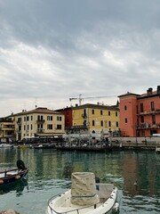 Picturesque view of a European city by the lake with boats and colorful buildings under a cloudy sky