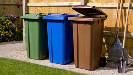 Color-Coded Recycling Bins and Garden Tools in Backyard &ndash; Waste Sorting and Sustainability Concept