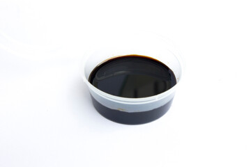 A sweet soy sauce inside a plastic cup, isolated on white.