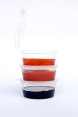 Tomato ketchup, sweet chili dan soybean sauce inside a plastic cup, isolated on white background.