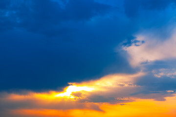 Dramatic cloudscapes meet a vibrant sunset. Sky transitions from deep blue to warm orange hues. Wonder of the beauty and power of the natural world
