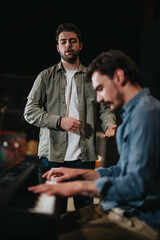 Musicians working together in a studio environment, focusing on piano playing and vocal performance.