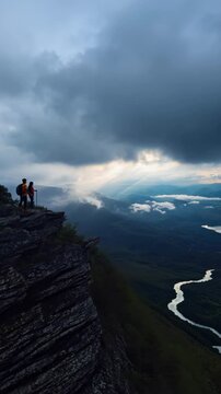 Hikers on a Cliff Edge Overlooking a Winding River and Valley at Dusk