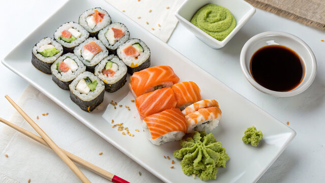 Sushi and rolls, on a white rectangular plate, with sauces