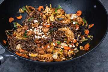 Yuba knots and veggie stir fry in cast iron wok, plant based Asian healthy food