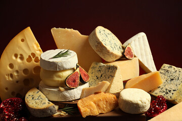 Different types of cheese, rosemary, figs and pomegranate on table