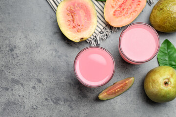Refreshing guava juice and fresh fruits on grey table, flat lay. Space for text