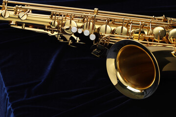 Fototapeta premium Jazz. One beautiful saxophone on dark blue fabric, closeup. Space for text