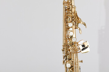 Golden soprano saxophone on light grey background, closeup. Space for text