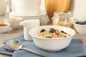 Tasty oatmeal with milk, blueberries and almonds in bowl served on table, closeup