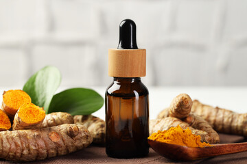 Tumeric oil, powder and roots on white table, closeup