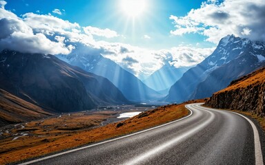 Winding road snaking through a mountainous region, flanked by steep slopes and dry grasslands, with snow-capped peaks and a sea of clouds in the distance, illuminated by the rays of sunlight creating 