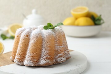 Delicious lemon cake with powdered sugar and mint on white wooden table, closeup