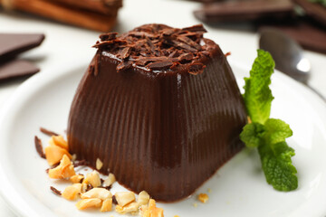 Tasty chocolate pudding with peanuts and mint on white table, closeup
