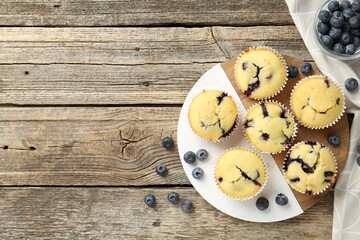 Delicious muffins with blueberries on wooden table, flat lay. Space for text