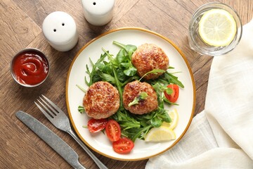 Delicious patties with greens, tomatoes, ketchup and drink on wooden table, flat lay