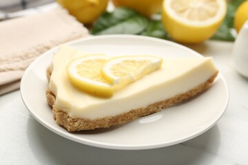 Piece of delicious lemon cheesecake on white marble table, closeup