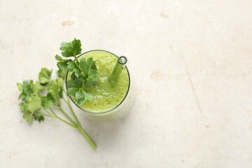 Healthy parsley smoothie in glass and leaves on light textured table, flat lay. Space for text