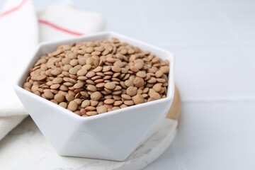 Raw brown lentils on white table, closeup