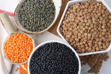 Different types of lentils on white table, flat lay