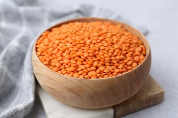 Red lentils in bowl on light table, closeup