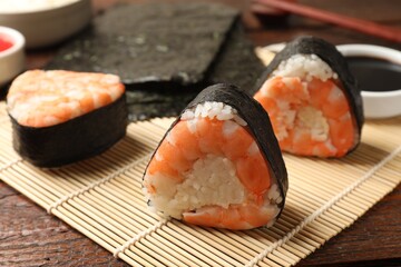 Tasty onigiri (Japanese rice balls) with shrimps on wooden table, closeup