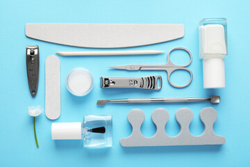 Set of different manicure tools and flower on light blue background, flat lay