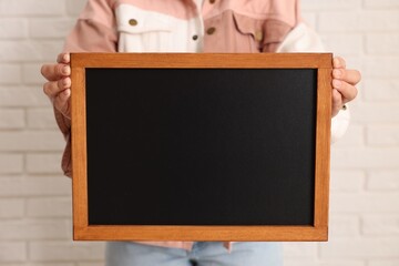 Woman holding blank small blackboard indoors, closeup