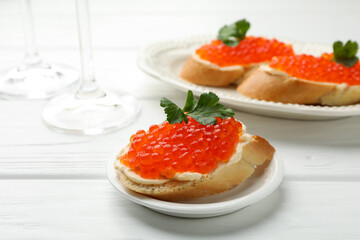 Tasty sandwiches with red caviar on white wooden table, closeup