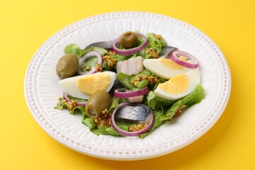 Delicious salad with herring, egg, mustard and vegetables on yellow background, closeup