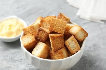 Tasty crispy croutons and sauce on grey textured table, closeup