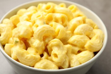 Delicious pasta with cheese sauce in bowl on table, closeup