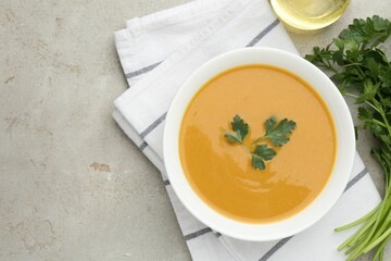 Delicious lentil cream soup with parsley and oil on light grey table, flat lay. Space for text