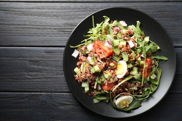 Delicious salad with brown rice on black wooden table, top view. Space for text