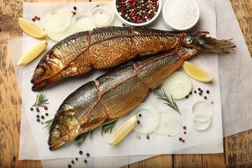 Smoked herrings and spices on wooden table, flat lay