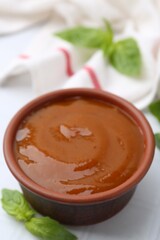 Tasty curry sauce and basil leaves on white tiled table, closeup