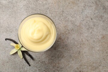 Tasty vanilla pudding, pods and flower on grey table, top view. Space for text