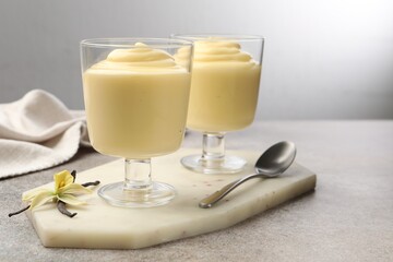 Tasty vanilla pudding, pods and flower on grey table