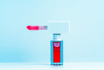 Red Lip Gloss Tube with Applicator Against Light Blue Background