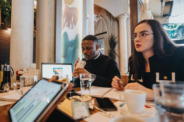 A diverse group of professionals gathers around a table, actively engaged in discussing business strategies and working together in a dynamic and collaborative office environment with modern decor.