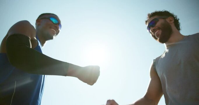 Active, men and fist bump for fitness in city for agreement, deal and team celebration. Below, people and partnership with blue sky of sports success, achievement and respect with solidarity in urban