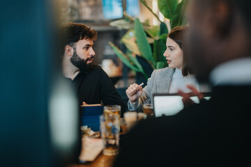 A group of colleagues engaged in a productive conversation and brainstorming session in a cafe setting, promoting collaboration and teamwork.