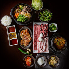 Korean BBQ set featuring premium wagyu beef, marinated pork ribs, and fresh vegetables with traditional sauces and sides, emphasizing rich flavors and variety